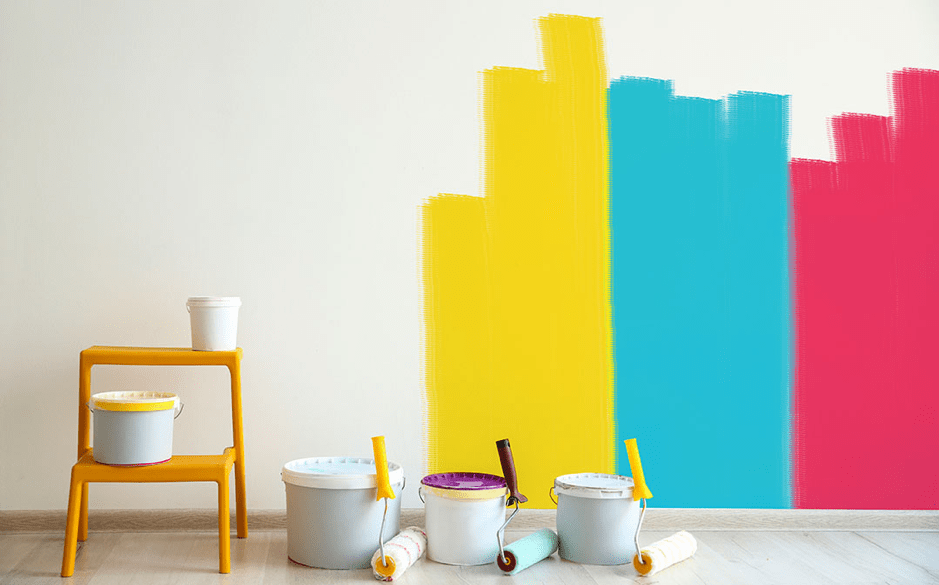 A room with colorful paint on the wall and a stool.
